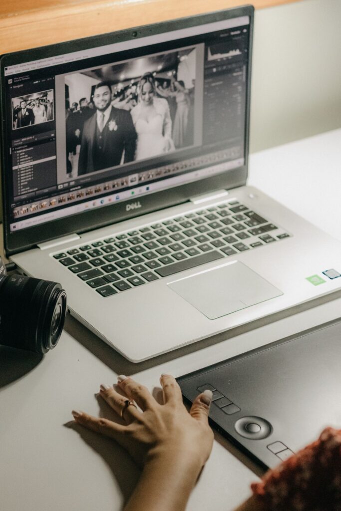 A person processes wedding photos on a laptop using a graphics tablet, showcasing digital editing tools